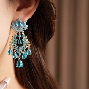 Dettaglio di orecchini pendenti vintage con zirconi blu e un elegante design a goccia