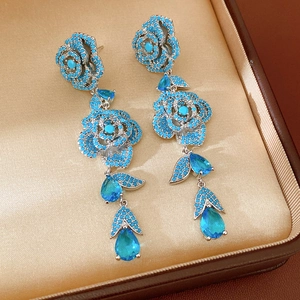 Primo piano dettagliato di eleganti orecchini a goccia in zircone blu e rosa in una scatola