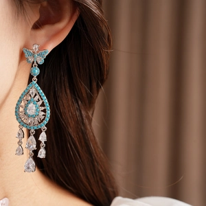 Primo piano di orecchini vintage a farfalla blu con pendenti a goccia in zircone.
