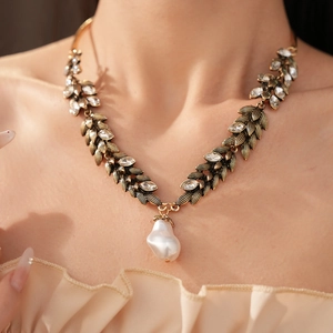 Detailed view of vintage wheat leaf necklace with crystals and baroque pearl pendant.