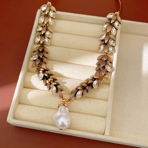 Detailed view of a vintage gold leaf wheat necklace with sparkling rhinestones and pearl.