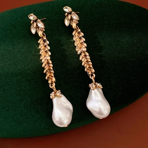 Detailed view of vintage gold leaf earrings with rhinestones and baroque pearls.