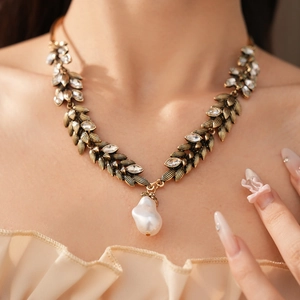 Detailed view of vintage gold wheat leaf necklace with baroque pearl and rhinestones