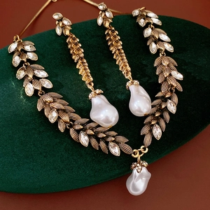 Detailed macro shot of vintage gold leaf necklace and earrings with baroque pearls