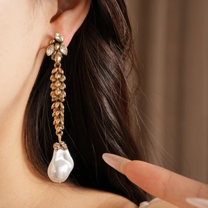 Macro view of vintage wheat ear earrings with a baroque pearl drop and rhinestones.