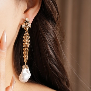 Detailed view of vintage gold wheat leaf earrings with large baroque pearl drop on model