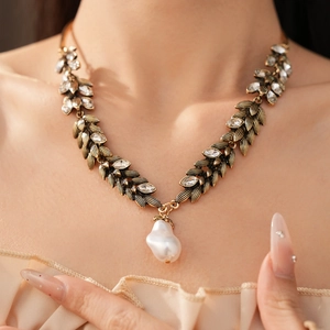 Close-up of vintage wheat leaf necklace with crystals and a baroque pearl pendant.