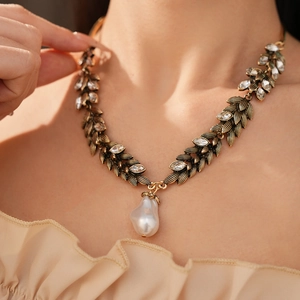 Close-up of vintage gold leaf necklace with crystals and large baroque pearl pendant