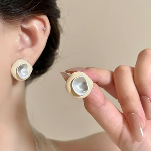 Close-up detail of irregular drip oil enamel earrings in cream and silver for women