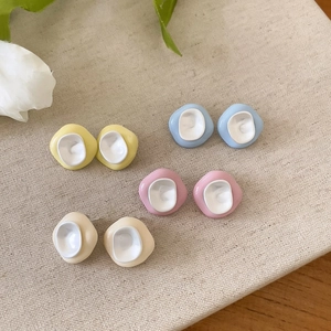 Close-up of four pairs of colorful irregular enamel stud earrings on beige cloth.