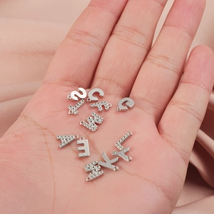 Vue détaillée des breloques en lettres argentées pour la création de bijoux DIY
