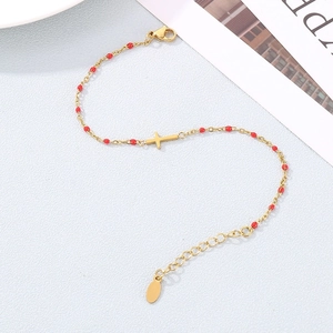 Détail du bracelet en acier inoxydable avec perles rouges et breloque croix dorée