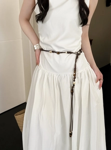 Nahaufnahme einer braunen Boho-Taillenkette mit Perlen an einem eleganten weißen Kleid.