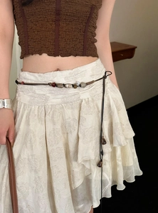 Nahaufnahme einer braunen Perlen-Taillenkette im Boho-Stil an einem cremefarbenen Kleid