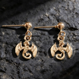 Vue détaillée des boucles d'oreilles dragon doré style punk sur roche noire