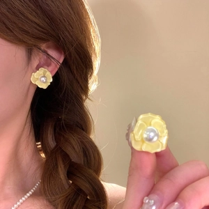 Detailed view of elegant yellow flower earrings with pearls shown worn on ear and close-up