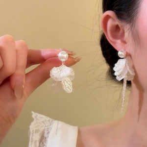 Close-up view of elegant white petal tassel earrings with pearls worn by a female model