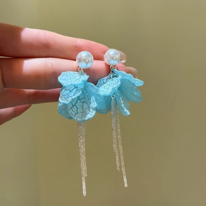 Detailed macro shot of blue petal tassel earrings featuring elegant white pearl studs