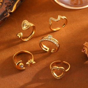 Dettaglio di cinque anelli d'oro in acciaio al titanio con cuori, lune e stelle.