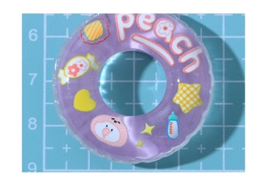 Macro shot of purple translucent cartoon swim ring resin charm with peach and heart patterns