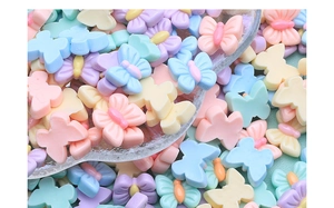 Macro view of mini resin butterfly charms in assorted pastel macaron colors for DIY