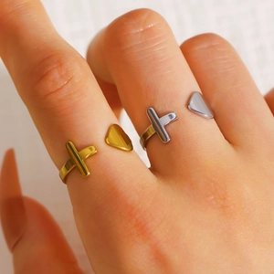 Nahaufnahme eines minimalistischen Edelstahlrings mit Kreuz und Dreieck, am Finger getragen.