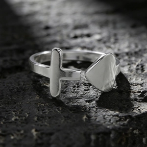 Detailansicht eines silbernen Edelstahlrings mit Herz- und Kreuzdesign in offener Form