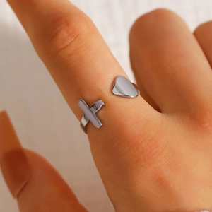 Detailaufnahme eines silbernen Edelstahlrings mit offenem Herz- und Kreuzdesign-Motiv.