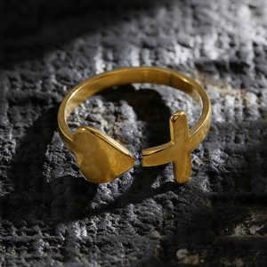 Detailaufnahme eines goldfarbenen Edelstahlrings mit Herz- und Kreuzmotiven.