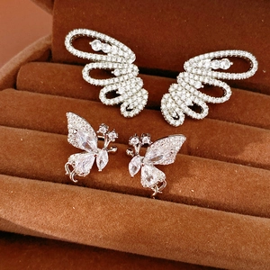 Close-up of butterfly zircon ear clips and wing earrings on a velvet jewelry tray.