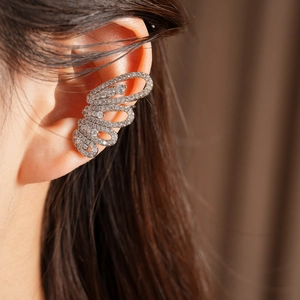 Close-up detail of a luxury sparkling zircon butterfly ear cuff worn on a model's ear.