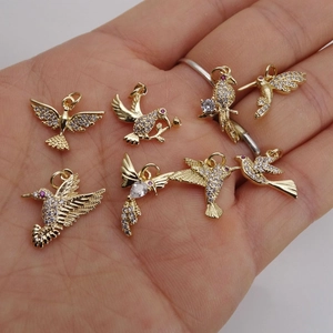 Handheld gold hummingbird charms with sparkling white and purple micro-set zircon crystals