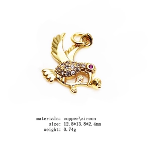 Macro detail of bird charm with clear zircons and red eye in gold plated copper