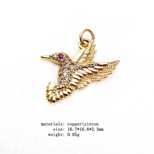 Macro detail of gold hummingbird pendant with sparkling cubic zirconia and red eye
