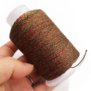 Primer plano de hilo metálico rojo, verde y dorado para tejer pulseras festivas DIY