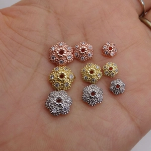 Vista macro di distanziatori a forma di fiore con zirconi in oro rosa e argento