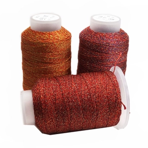 Primer plano de hilos de bordar metálicos en naranja, púrpura y rojo para creación de joyas