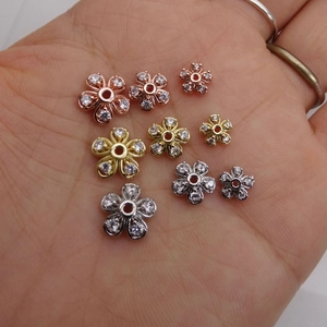 Dettaglio di perline distanziatrici a fiore con zirconi in oro, oro rosa e argento