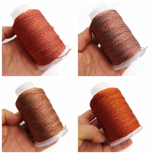 Detalle de hilos metálicos brillantes en rojo y dorado para tejido a mano y DIY