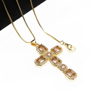 Detailed close-up of a golden cross pendant with champagne zircon and lobster clasp