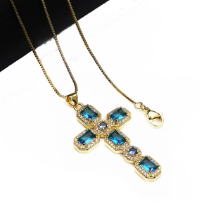 Close-up of golden cross pendant with blue zircons and lobster clasp on link chain