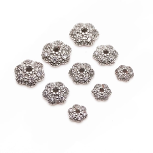 Dettaglio macro di nove dimensioni di distanziatori per fiori in zircone per gioielli fai-da-te