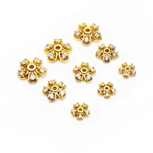 Dettaglio di distanziatori a fiore placcati oro con zirconi per creazioni gioielli fai-da-te