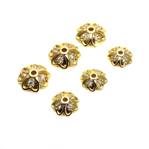 Dettaglio macro di distanziali a fiore placcati oro con zirconi per creazioni fai da te