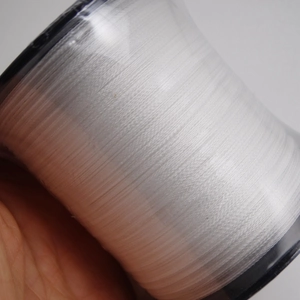 Close-up of durable white nylon pearl stringing wire for DIY jewelry on a black spool