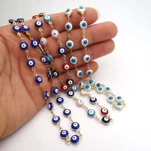 Detailansicht bunter Evil Eye Perlenketten mit goldenen Metallrahmen in der Hand