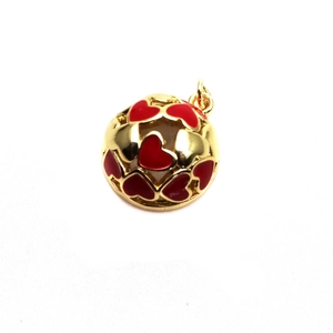 Detail einer goldenen Kugel mit hohlen, rot getropften Herzmustern als Anhänger