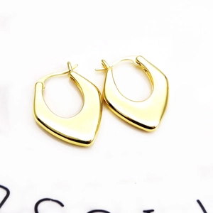 Macro detail of 18K gold plated teardrop huggie earrings with polished geometric finish