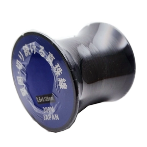 Macro detail of 0.6mm black Japan pearl thread roll with blue label on white background
