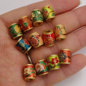 Cloisonné flower beads in varied colors shown in palm for size and intricate detail